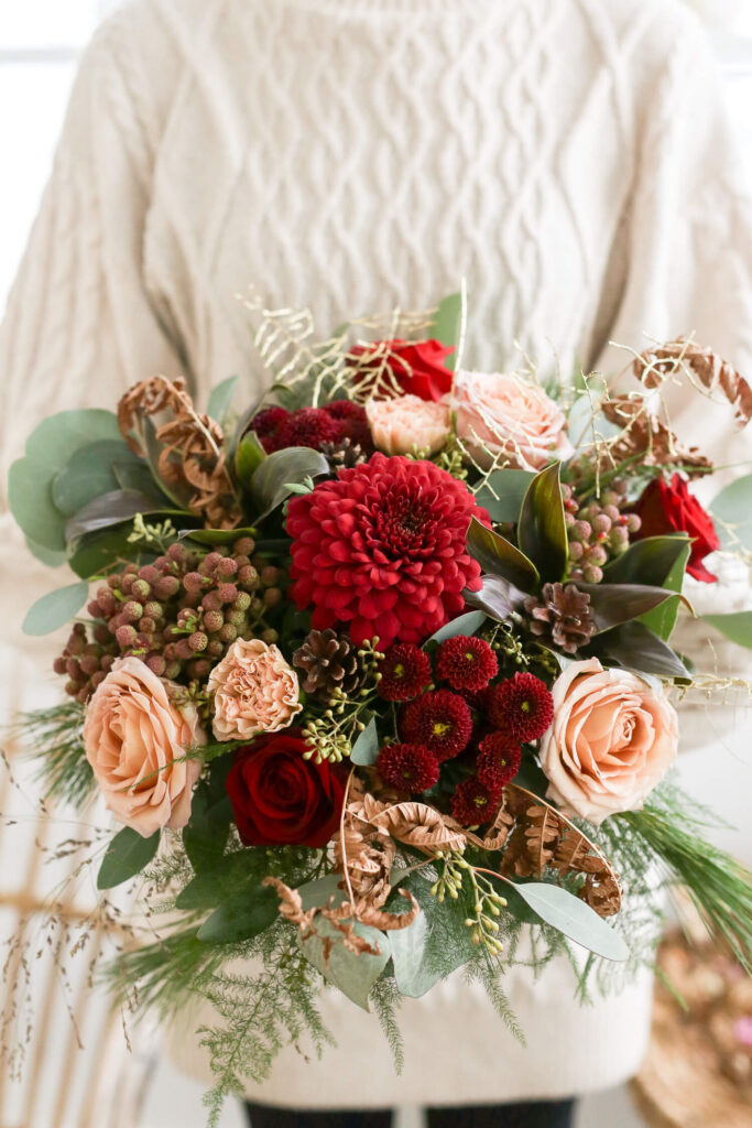 Joulukimppu. Kimpussa punaisia, puuterin ja vaalean värisiä leikkokukkia. Ripaus kultaa myös löytyy kimpusta.