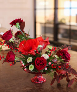 Joulun punainen leikkokukkaasetelma jalallisessa astiassa