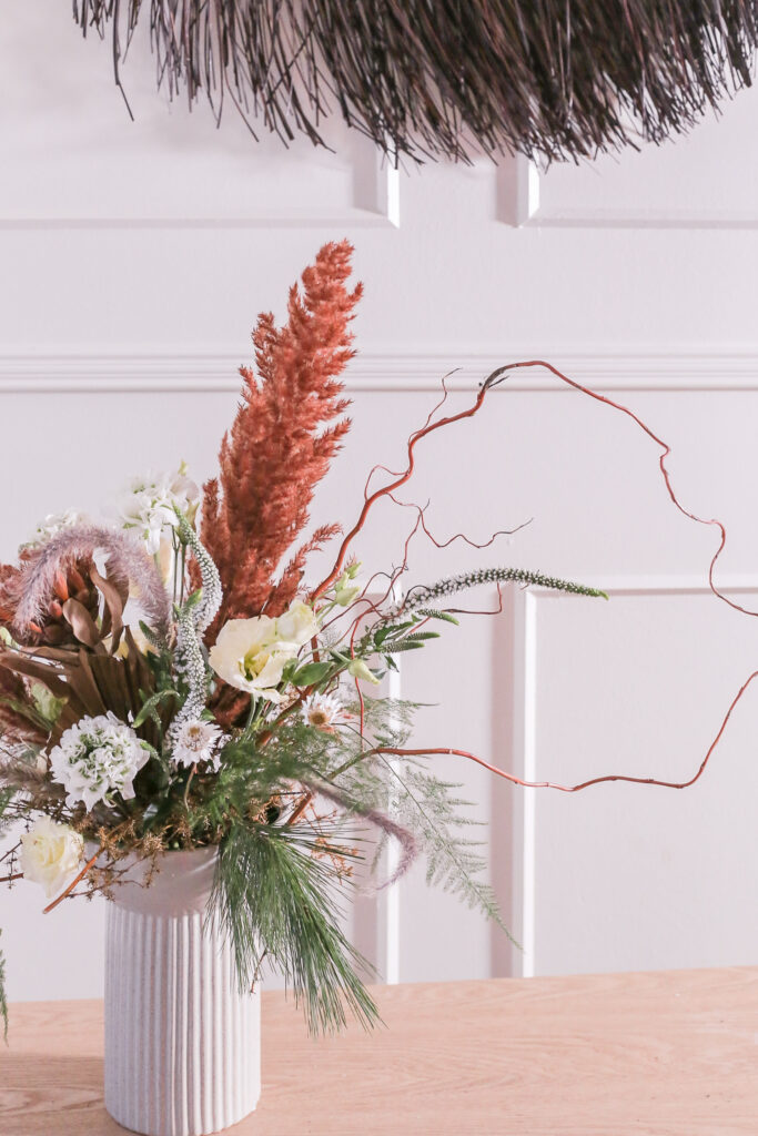 epäsymmetrinen kimppu sidottu vaalean korkeaa maljakkoon